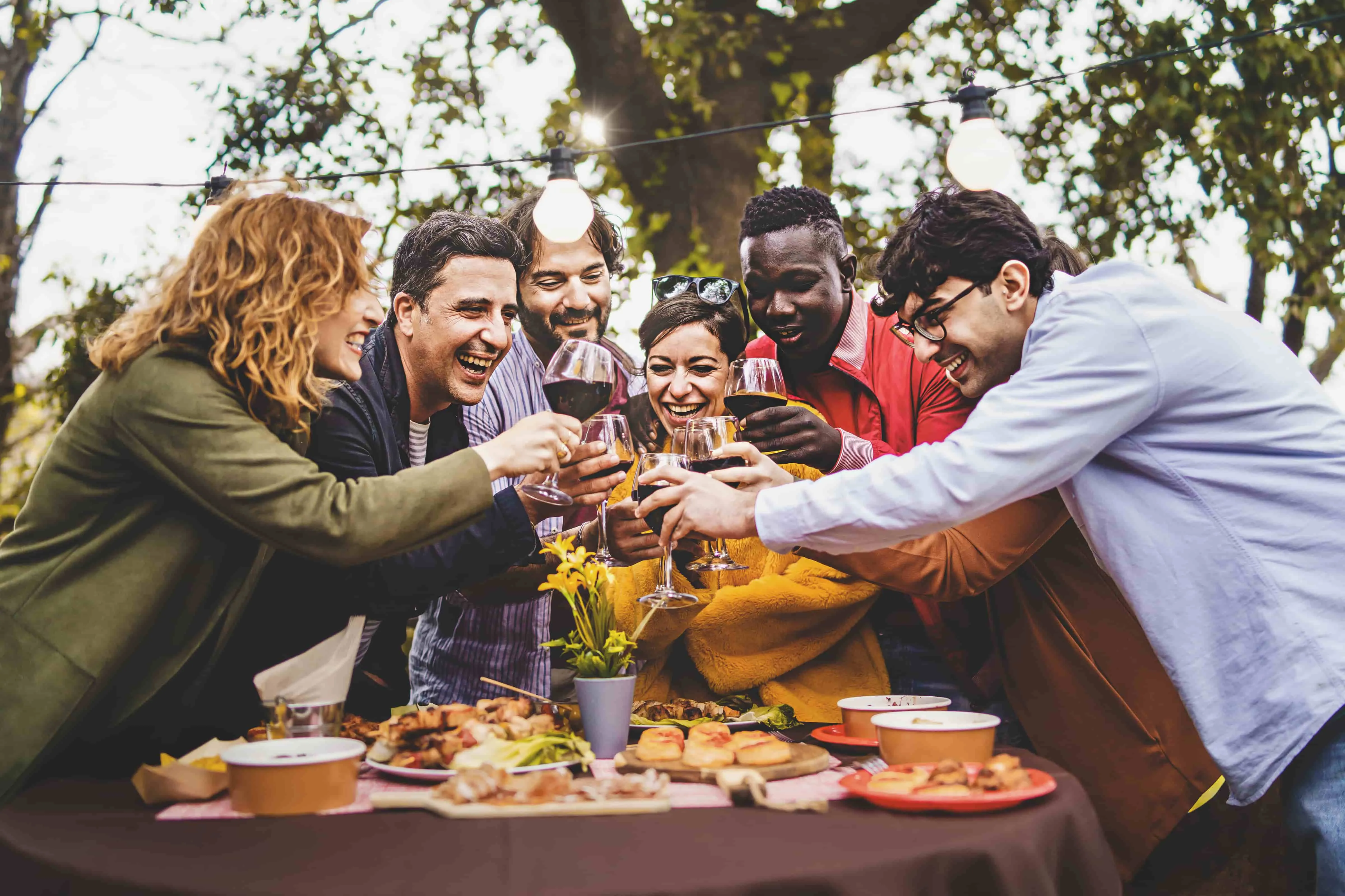 Company of cheerful friends having fun toasting pic nic in farmhouse countryside
